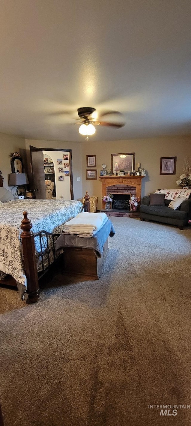 carpeted bedroom featuring ceiling fan and a fireplace