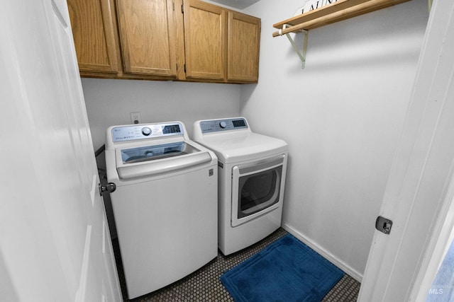 clothes washing area featuring baseboards, cabinet space, and separate washer and dryer