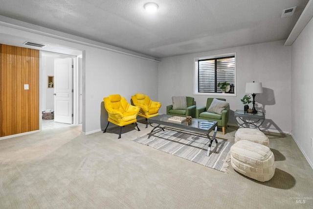 living area featuring visible vents, carpet flooring, baseboards, and wooden walls