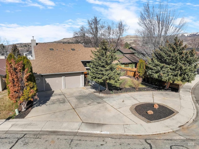 view of front facade with an attached garage, a shingled roof, fence, concrete driveway, and a mountain view