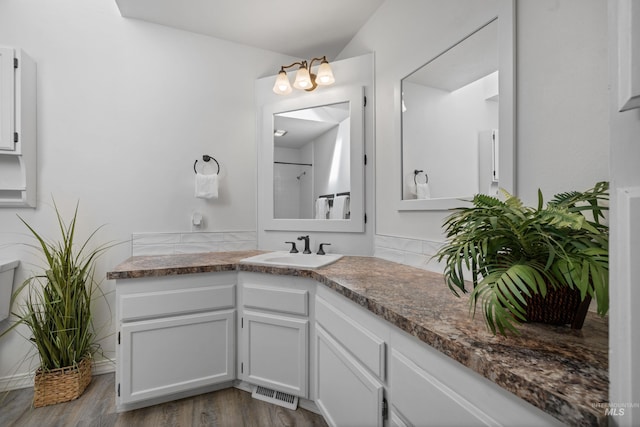 bathroom with vanity, wood finished floors, visible vents, and a shower