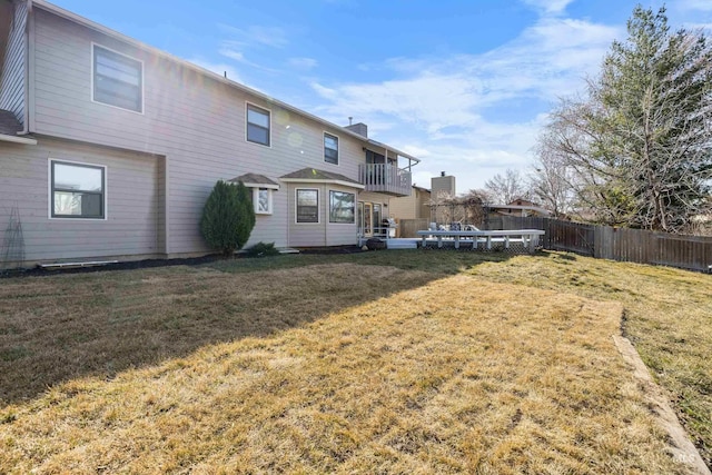 rear view of property featuring a yard, fence, and a chimney