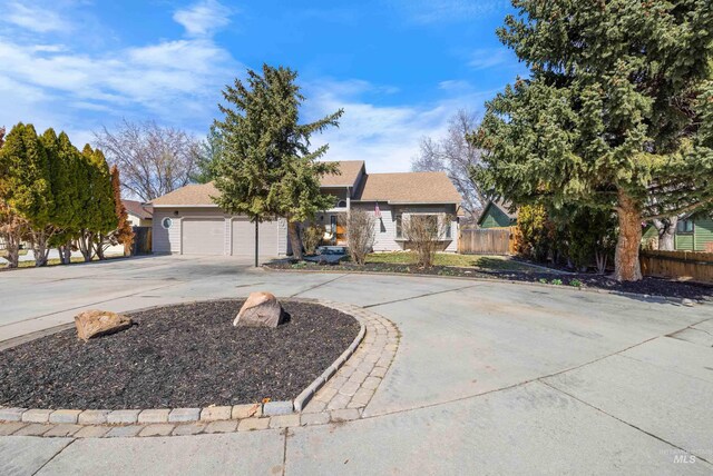 ranch-style house featuring concrete driveway, an attached garage, and fence