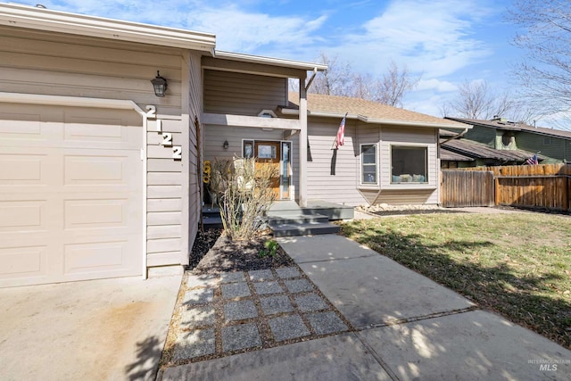 property entrance with a lawn, a garage, and fence