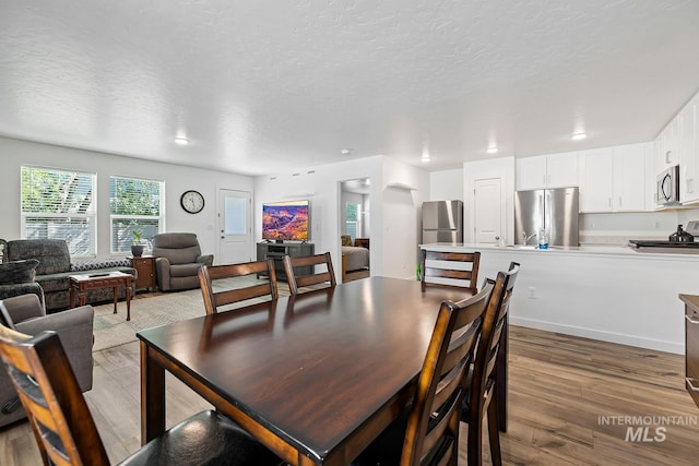 11002 W Hidden Point St, Star, ID 83669 - dining room featuring light wood-style flooring, arched walkways, and a textured ceiling