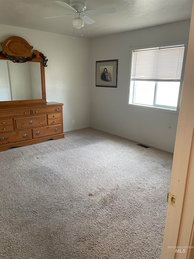 unfurnished room with ceiling fan and carpet