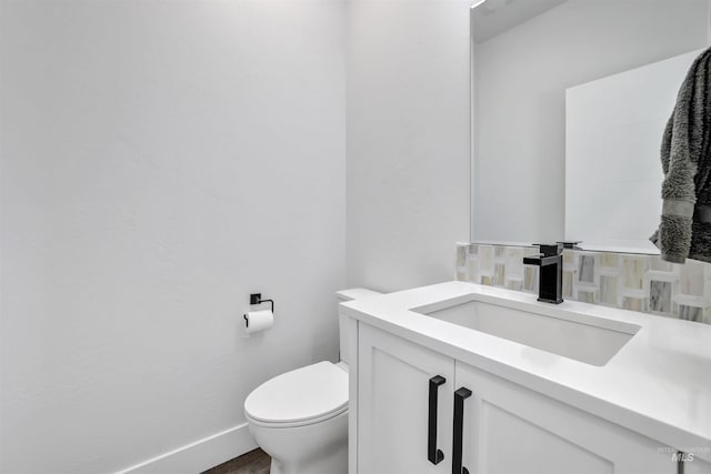 half bath with toilet, vanity, and baseboards