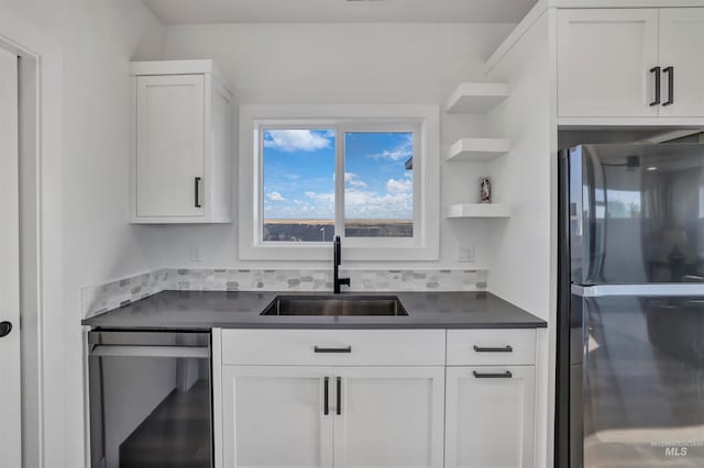 kitchen featuring black fridge, stainless steel dishwasher, sink, and white cabinets