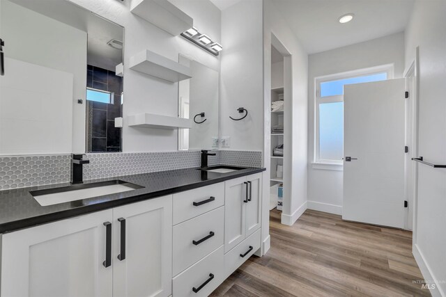 bathroom with walk in shower, vanity, hardwood / wood-style floors, and tasteful backsplash