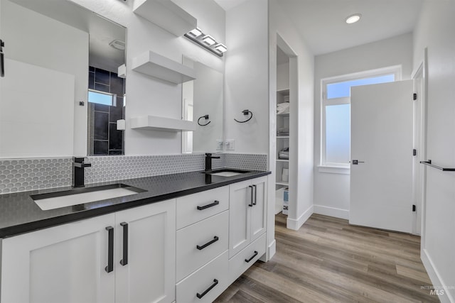 bathroom with double vanity, a sink, baseboards, and tasteful backsplash