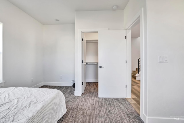 bedroom featuring dark wood-type flooring, a closet, and a walk in closet