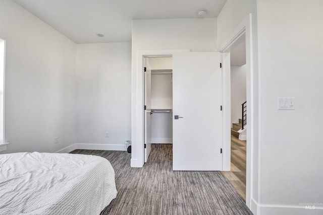 bedroom with a closet, a walk in closet, and baseboards
