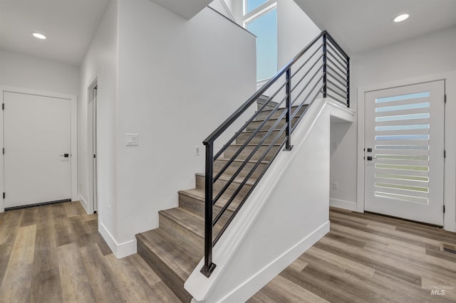 stairs featuring wood finished floors, recessed lighting, and baseboards
