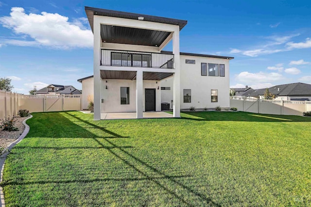 rear view of property featuring a balcony, a lawn, and a patio area