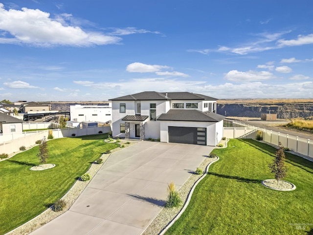 prairie-style home with driveway, fence, a front yard, stucco siding, and a garage