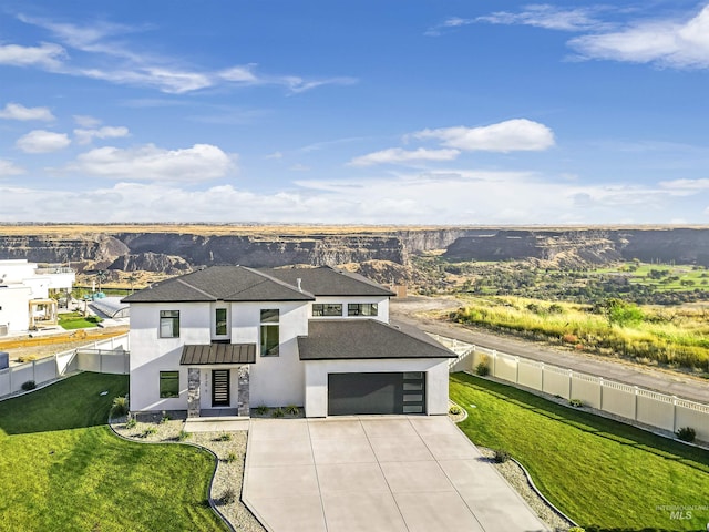 view of front of home with concrete driveway, roof with shingles, a front yard, stucco siding, and a fenced backyard