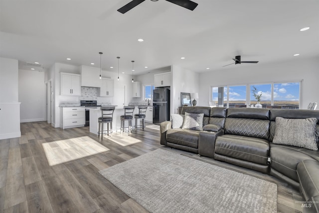 living area featuring light wood-style floors, a ceiling fan, and recessed lighting