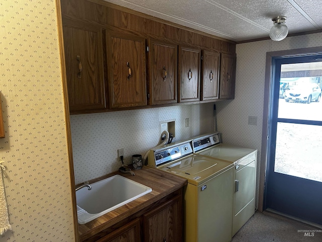 laundry room with cabinets, a textured ceiling, washing machine and dryer, and sink