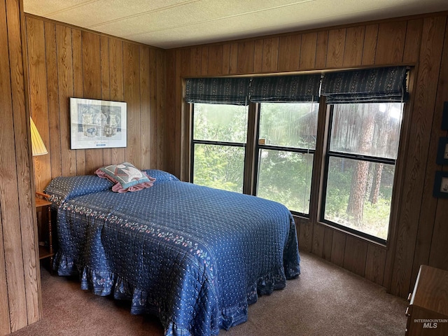 bedroom with dark colored carpet and wood walls