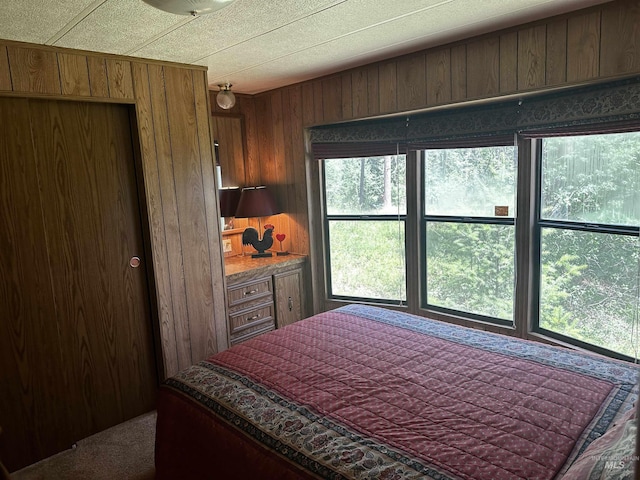 bedroom featuring multiple windows and wood walls