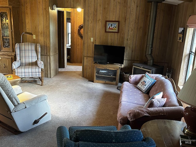 living room with carpet, wood walls, and a wood stove