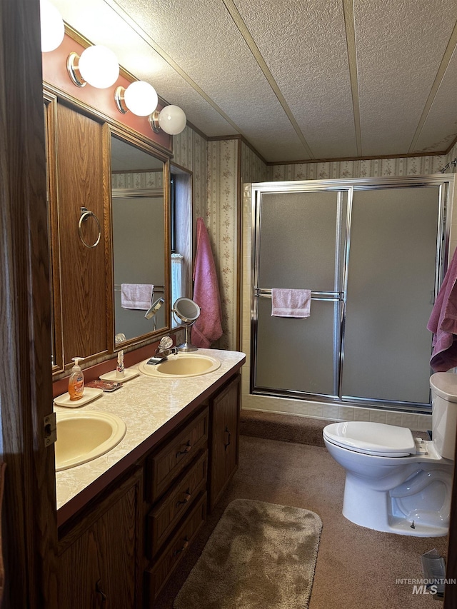 bathroom featuring a shower with door, vanity, a textured ceiling, and toilet