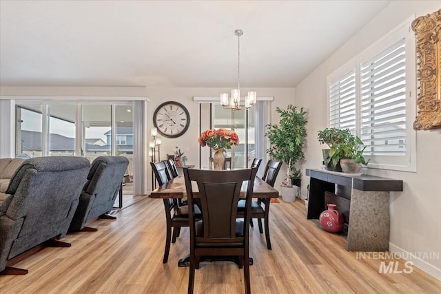 dining room with light hardwood / wood-style flooring and a chandelier