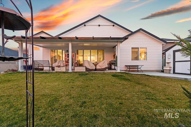 back house at dusk with a yard and a patio area