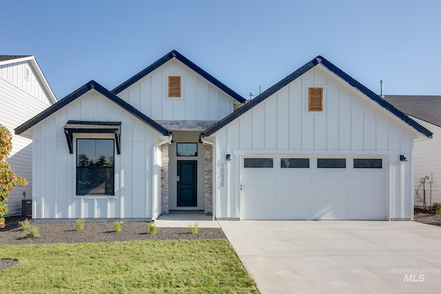 modern inspired farmhouse featuring concrete driveway, board and batten siding, a front yard, and a garage