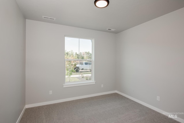 spare room featuring carpet flooring, visible vents, and baseboards