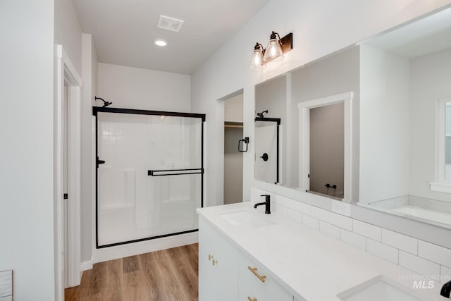 full bathroom with a sink, a stall shower, visible vents, and wood finished floors