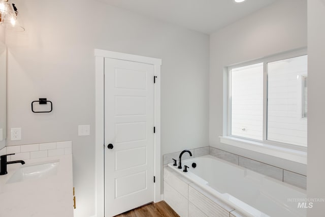 full bathroom with a garden tub, wood finished floors, and vanity