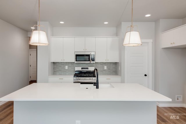 kitchen with stainless steel appliances, tasteful backsplash, wood finished floors, pendant lighting, and baseboards
