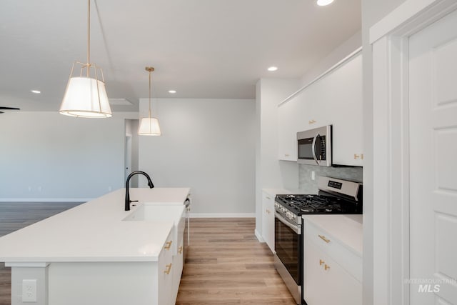 kitchen with light wood-style floors, appliances with stainless steel finishes, baseboards, and a sink