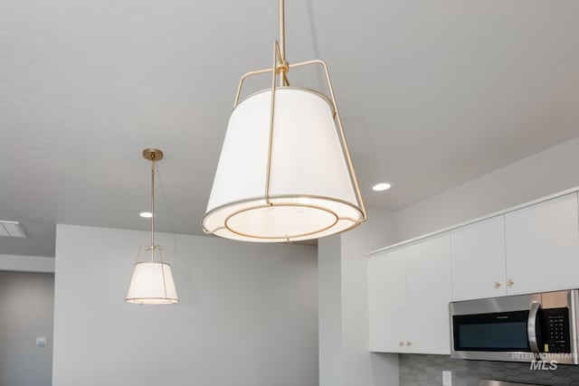 details featuring white cabinetry, visible vents, recessed lighting, and stainless steel microwave