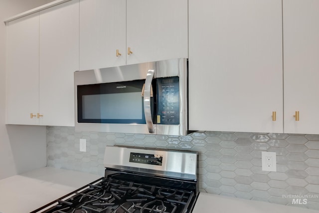 kitchen featuring white cabinets, light countertops, appliances with stainless steel finishes, and decorative backsplash