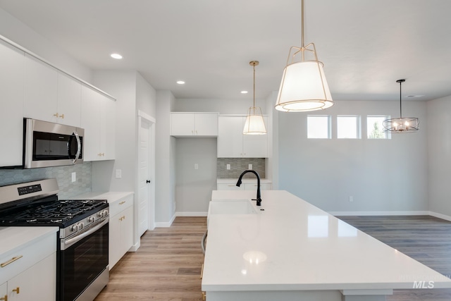 kitchen featuring light countertops, appliances with stainless steel finishes, tasteful backsplash, and light wood-type flooring