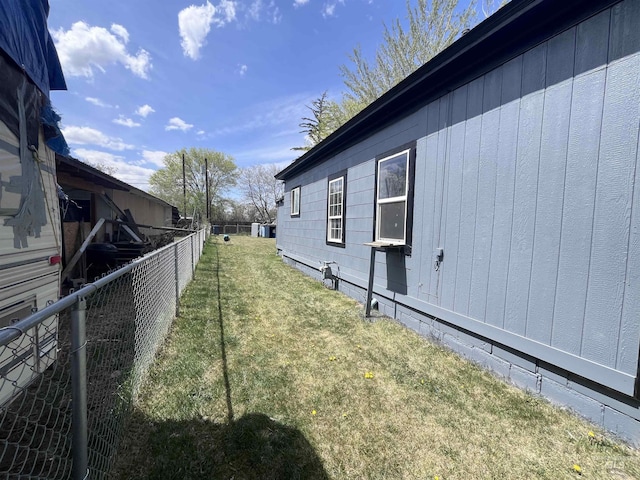 view of side of home featuring a lawn and fence