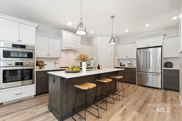 4153 E Raincloud Ln, Boise, ID 83716 - kitchen featuring appliances with stainless steel finishes, backsplash, light countertops, a kitchen breakfast bar, and recessed lighting