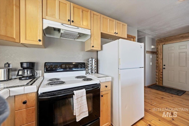 kitchen featuring tile countertops, light brown cabinetry, black electric range oven, white fridge, and light hardwood / wood-style flooring