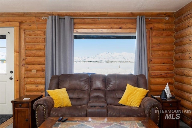 living room featuring a mountain view, a wealth of natural light, and log walls