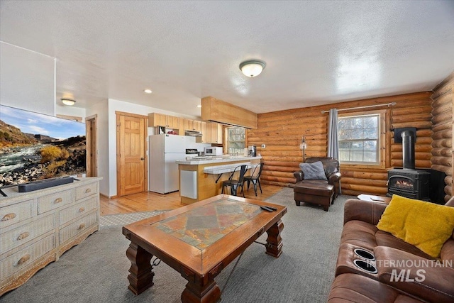 carpeted living room featuring a textured ceiling, rustic walls, and a wood stove