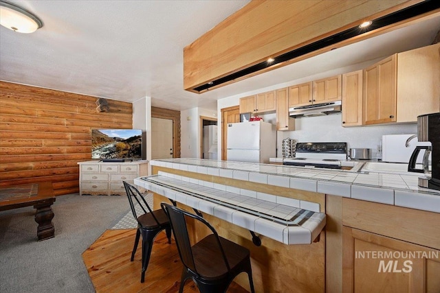 kitchen with range with electric cooktop, tile countertops, light brown cabinetry, rustic walls, and white refrigerator