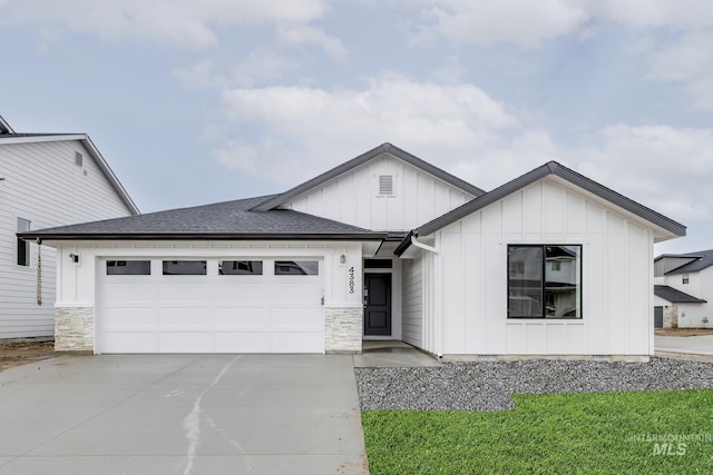 view of front of home with concrete driveway, board and batten siding, an attached garage, and stone siding