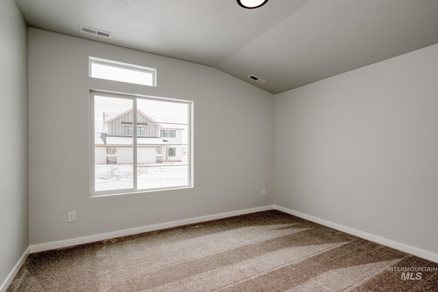 carpeted empty room featuring lofted ceiling, baseboards, and visible vents