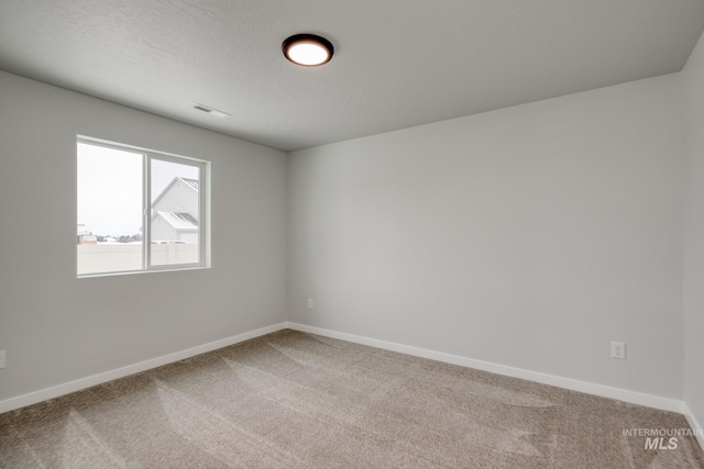 empty room featuring carpet flooring, visible vents, and baseboards