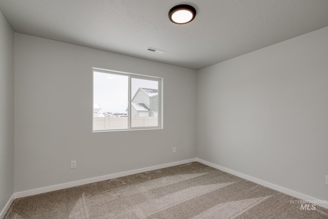 carpeted empty room featuring visible vents and baseboards