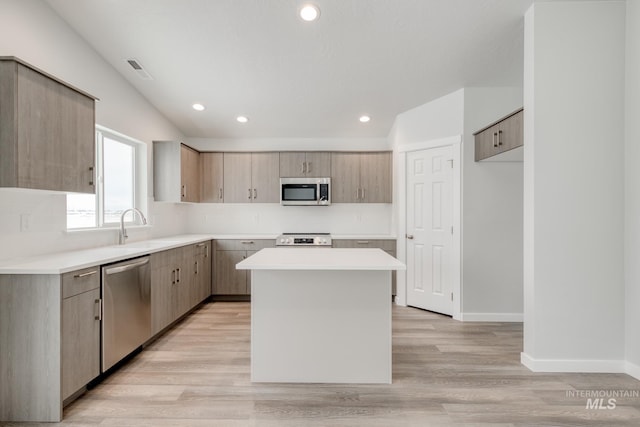 kitchen featuring light wood-style flooring, a sink, a kitchen island, light countertops, and appliances with stainless steel finishes