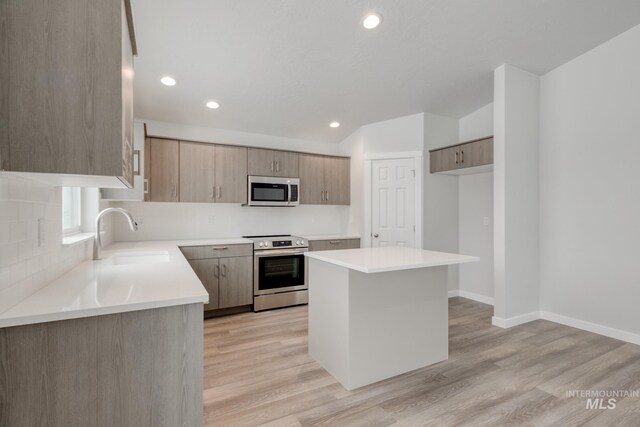 kitchen with light wood-style floors, stainless steel appliances, decorative backsplash, and a sink