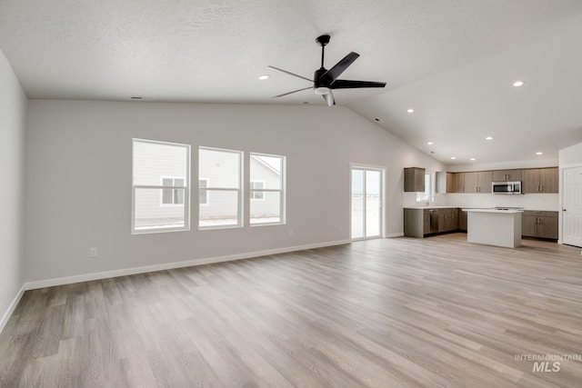 unfurnished living room featuring lofted ceiling, a ceiling fan, recessed lighting, baseboards, and light wood-type flooring